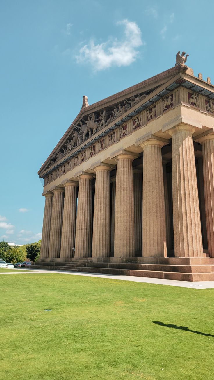 a man standing in front of a tall building with many columns on top of it