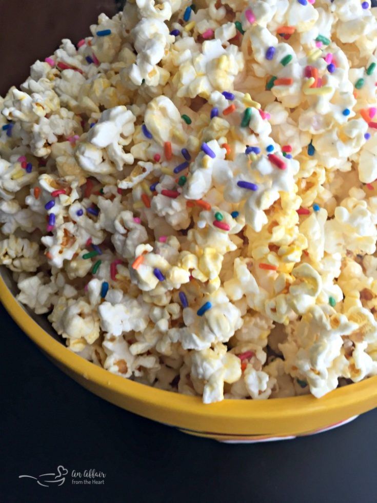 a yellow bowl filled with popcorn and sprinkles on top of a table