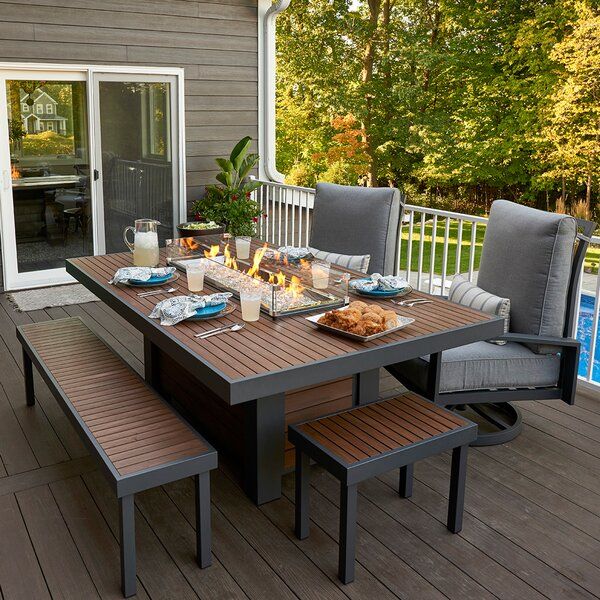 an outdoor table and chairs with a fire pit on the back deck next to a swimming pool