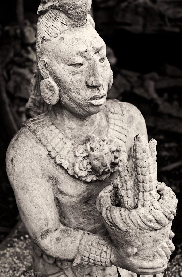 black and white photograph of a buddha statue holding a corn cob in his hands