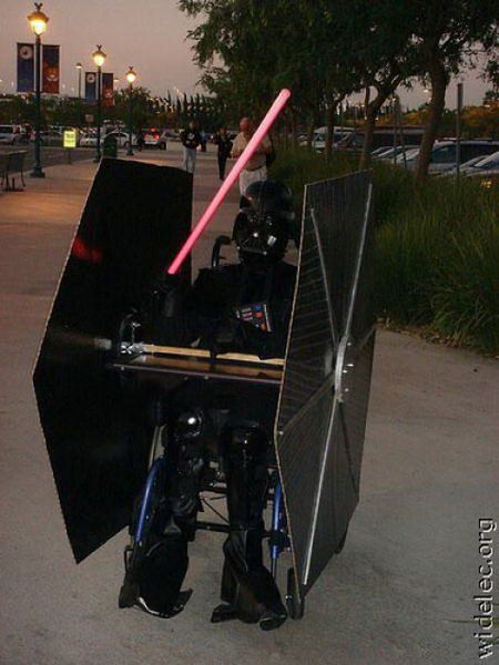 darth vader costume on display at an outdoor event with lightsabed in the background