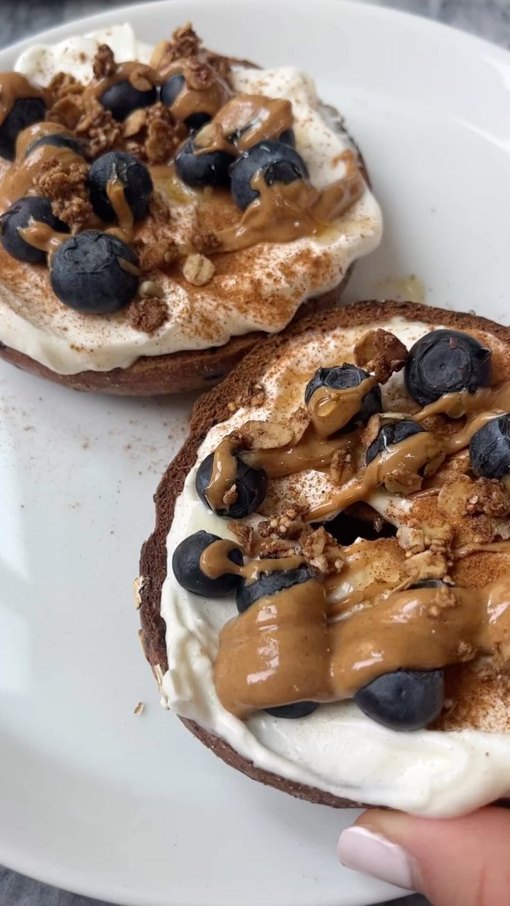 two toasted breads with blueberries and whipped cream are on a white plate