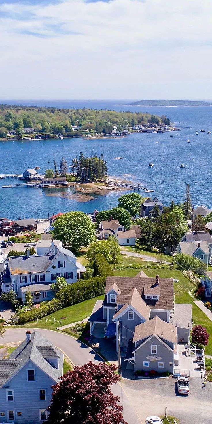 an aerial view of some houses by the water with boats in the water behind them