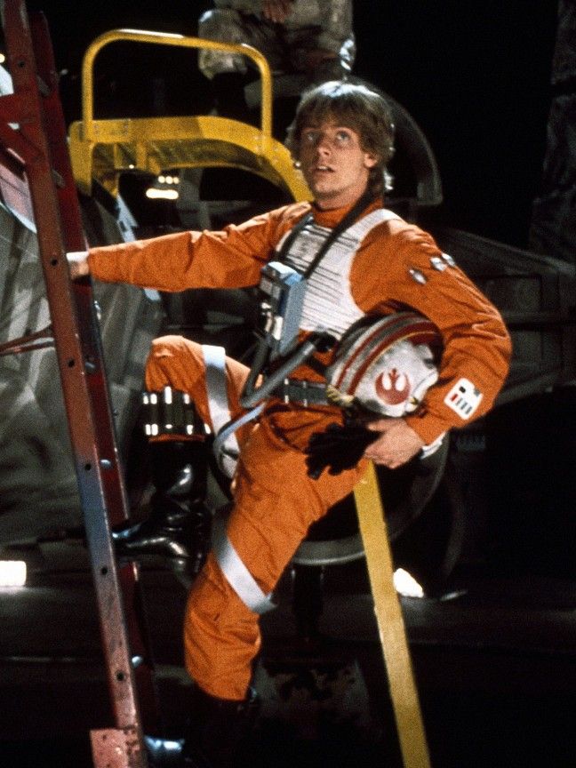 a man in an orange space suit climbing up a ladder with his hand on the side