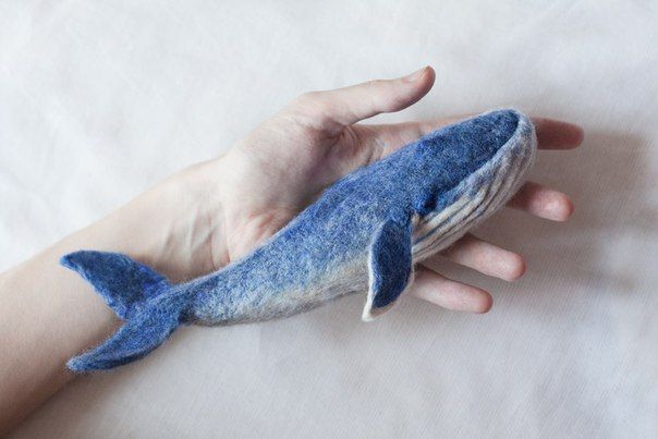 a hand is holding a blue whale toy