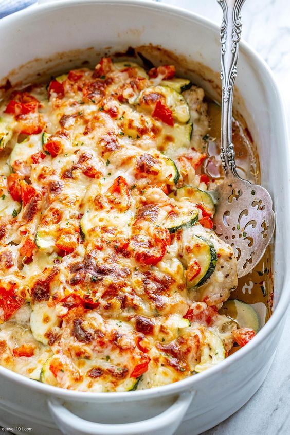 a casserole dish with zucchini, tomatoes and other vegetables in it