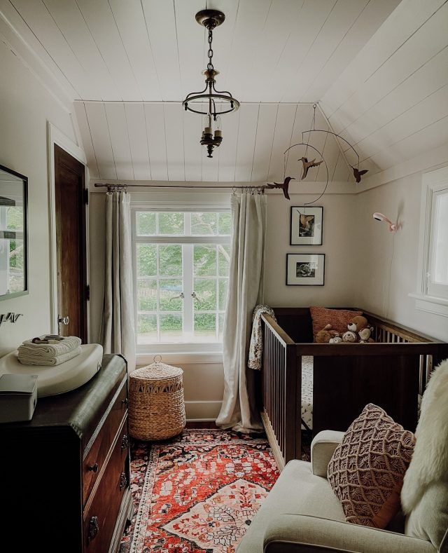 a baby's room with a crib, rocking chair, and window in it