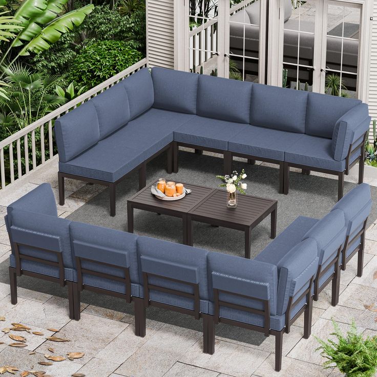 an outdoor seating area with blue couches and coffee table on the patio, surrounded by greenery