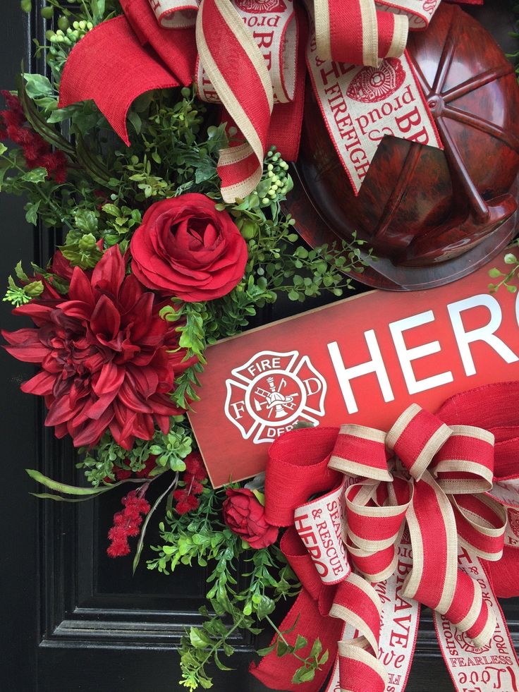 a fire department wreath with red flowers and ribbon around it that says hero on the front door