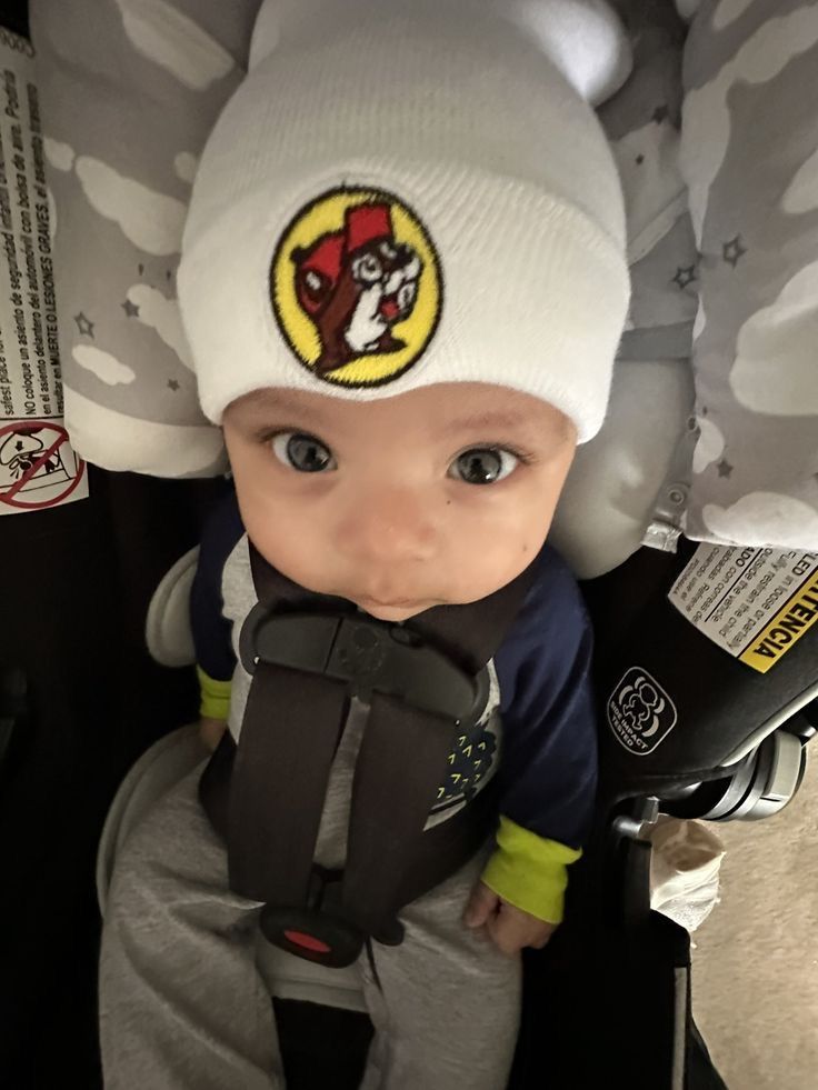 a baby wearing a white hat and sitting in a stroller