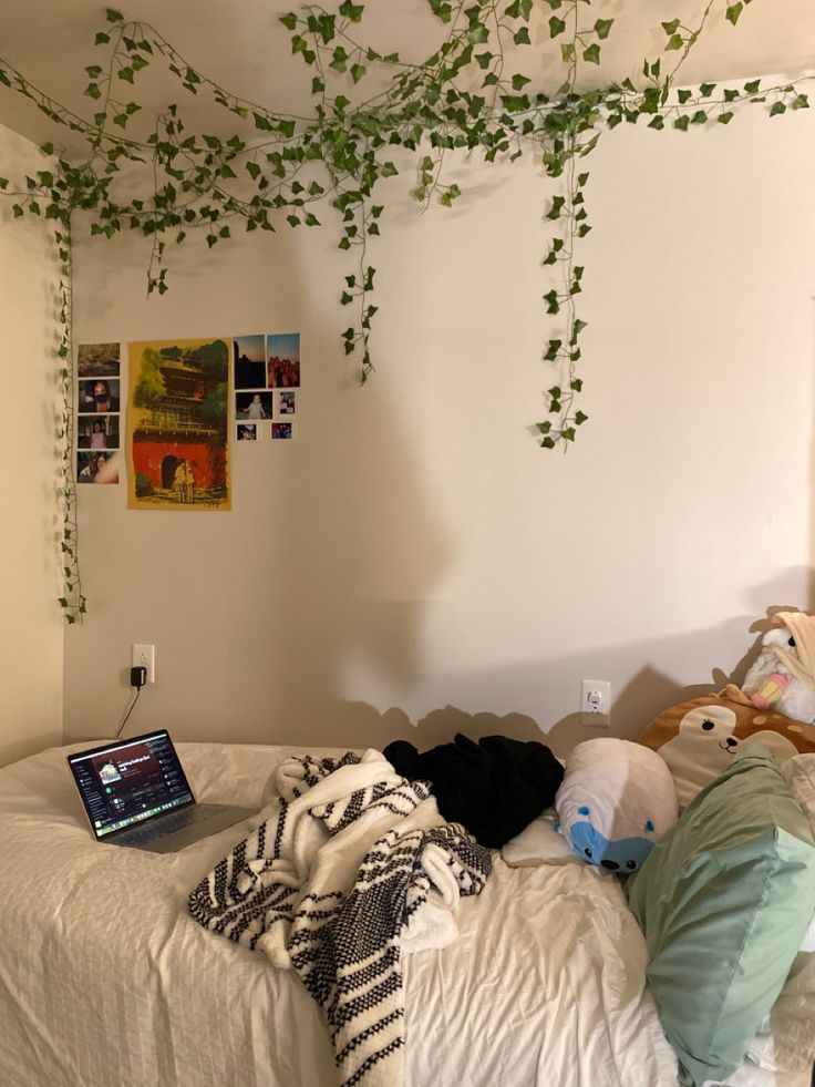 a laptop computer sitting on top of a bed under a green vine covered tree branch