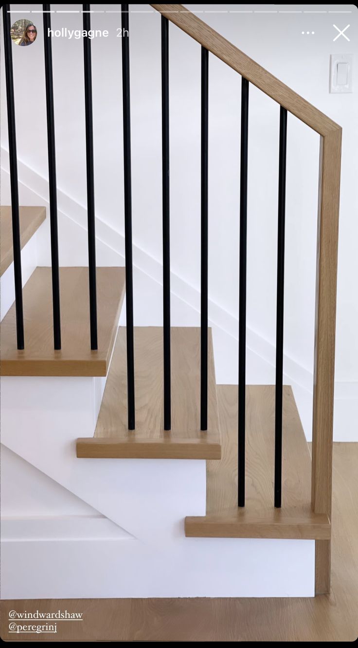 a set of stairs with black railings and wood handrails