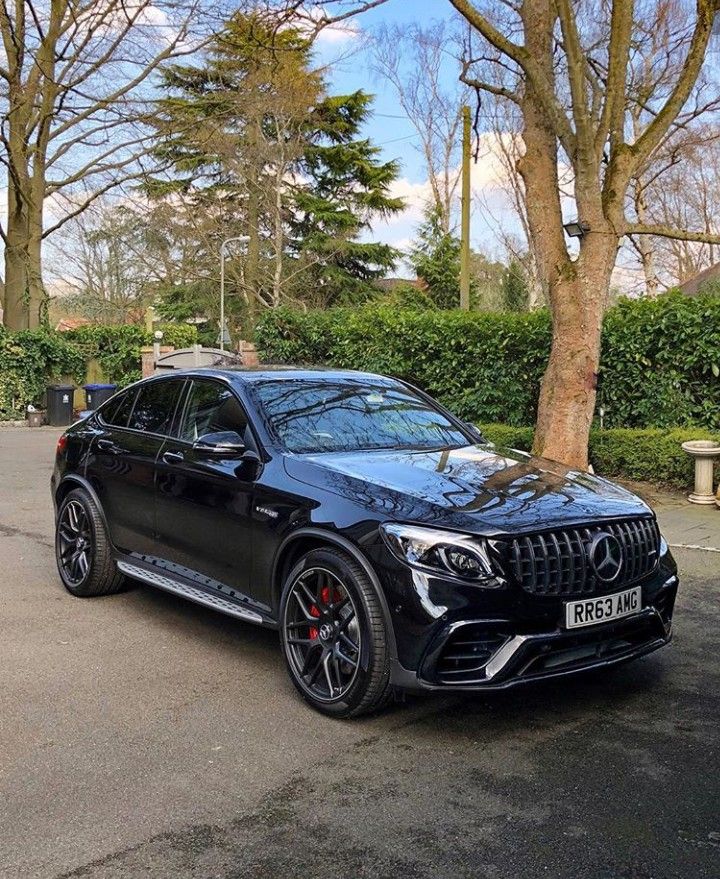 a black mercedes gle is parked in front of some trees