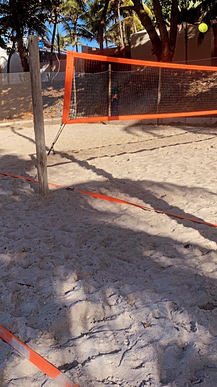 an orange tennis net is in the sand