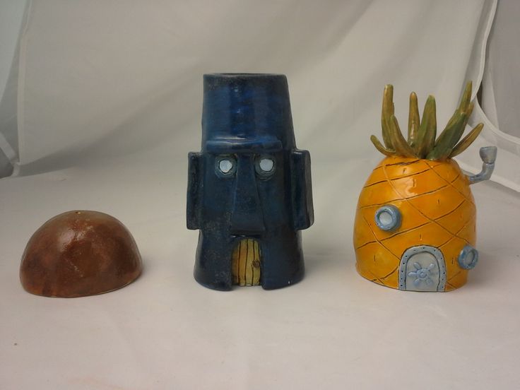 three ceramic objects sitting next to each other on a white tableclothed background,