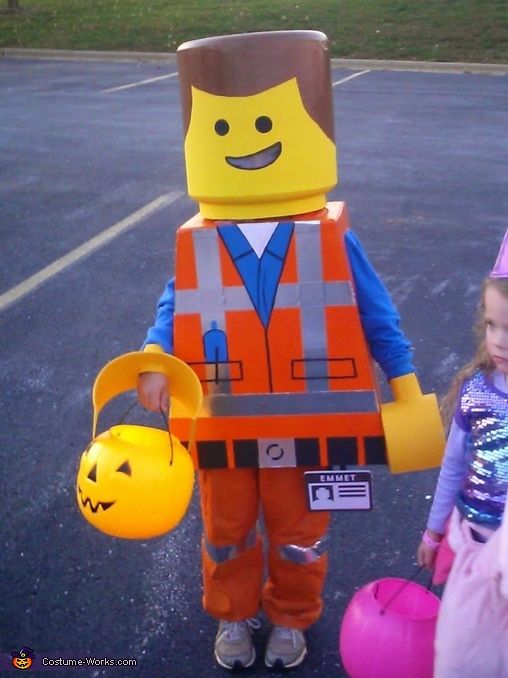 two children dressed up as legos and one is holding an orange bucket while the other holds