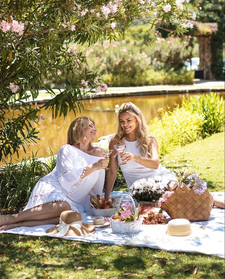 two women sitting on the grass having a picnic