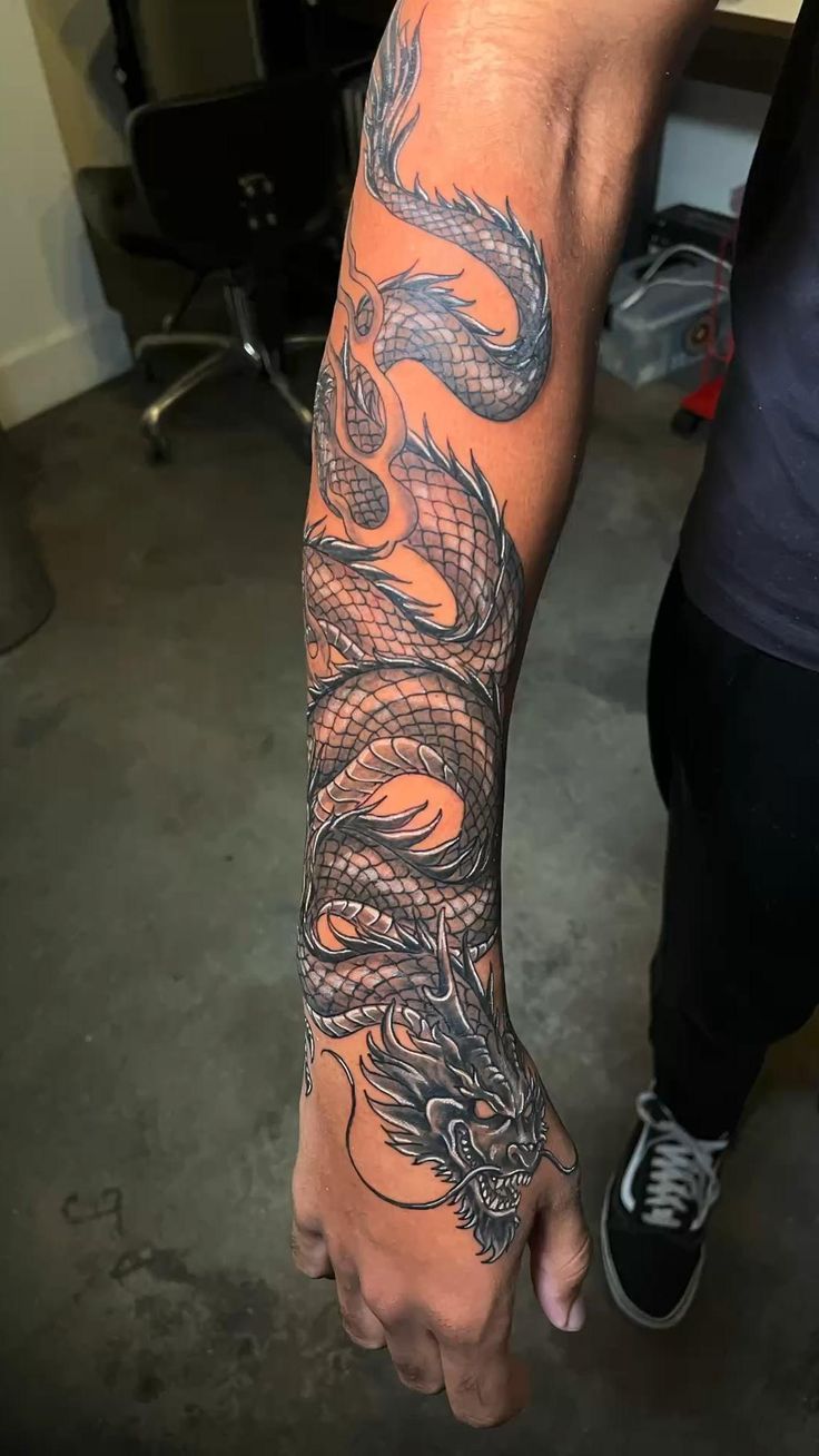 a man's arm with a dragon tattoo on it, in the middle of his hand