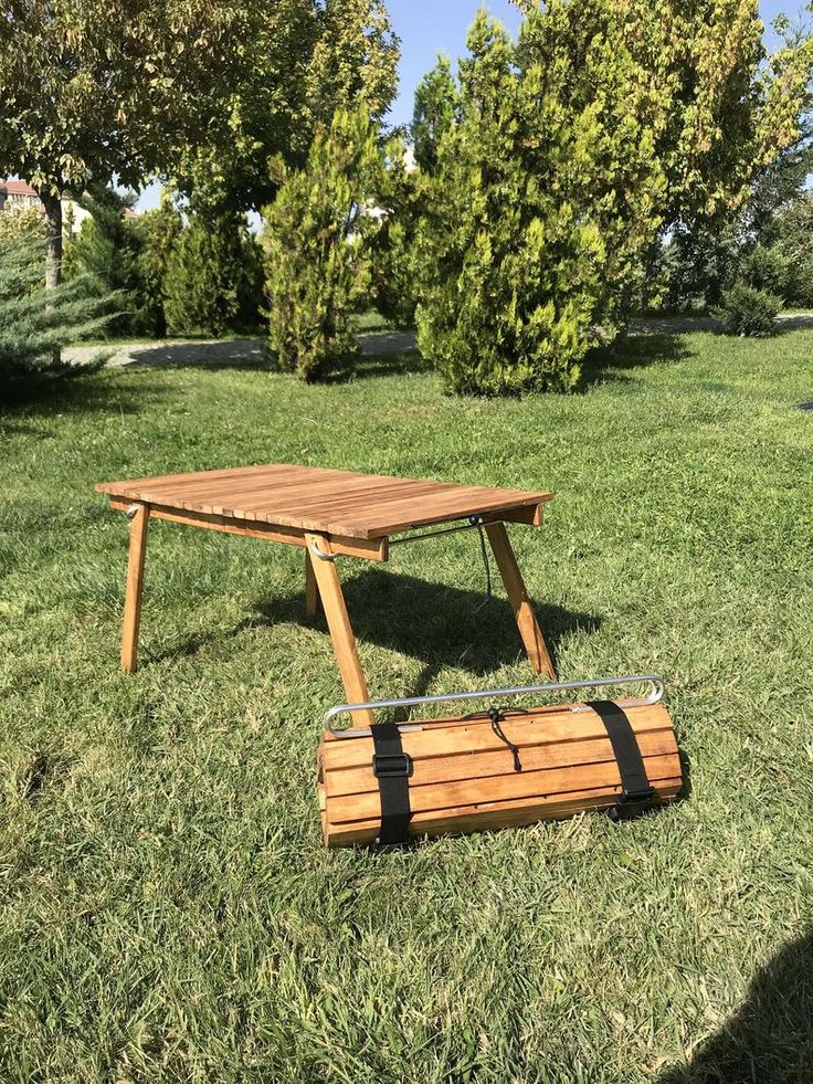 a picnic table made out of wooden planks in the middle of a grassy field