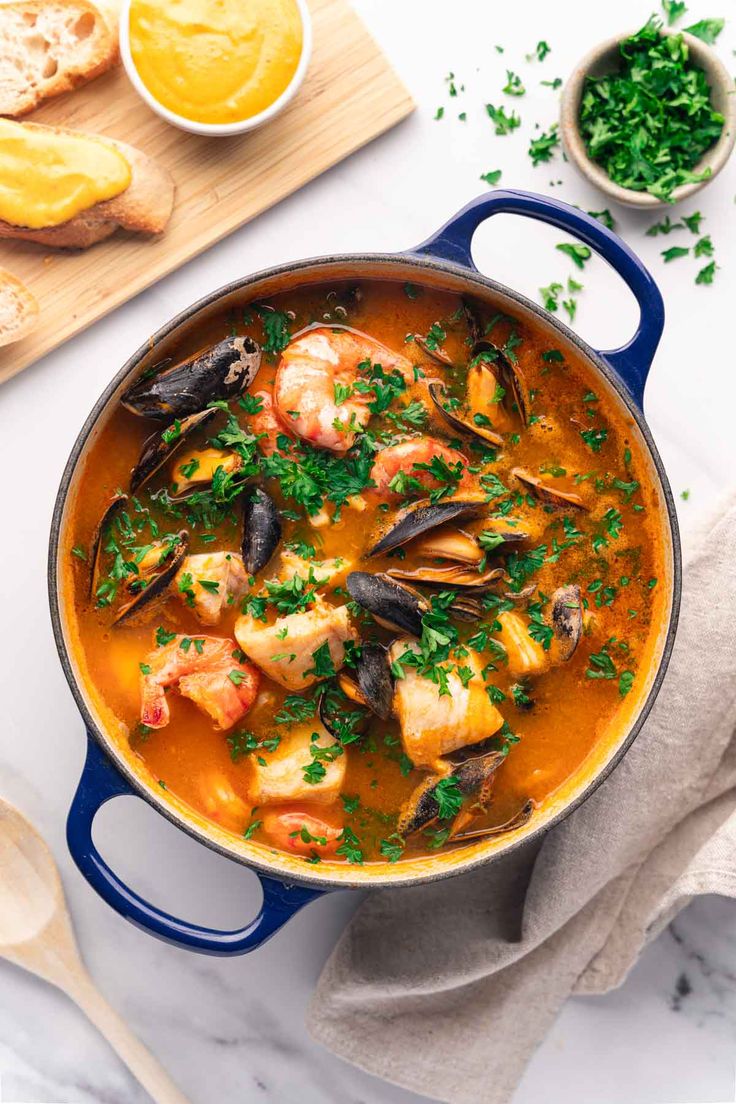 a blue pot filled with seafood and mussels on top of a white table