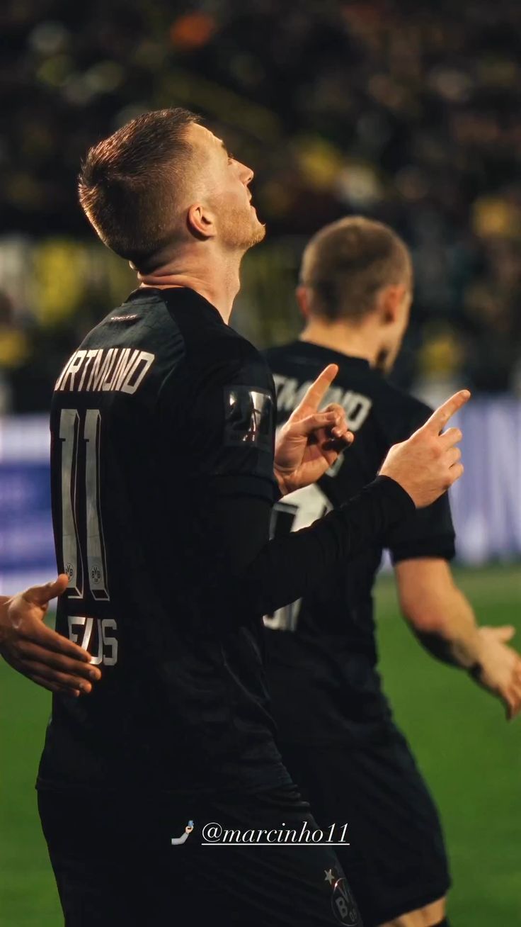 two men standing on top of a soccer field with their hands up in the air