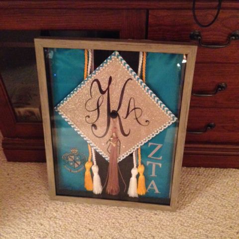 a graduation cap and tassel with the letter glaa on it in front of a dresser