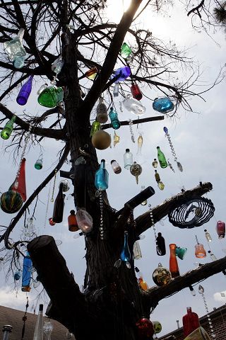 a tree filled with lots of different colored glass bottles