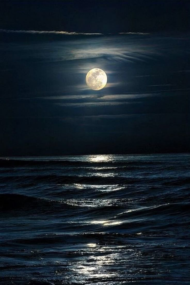 the full moon is shining over the ocean and waves in the water at night time