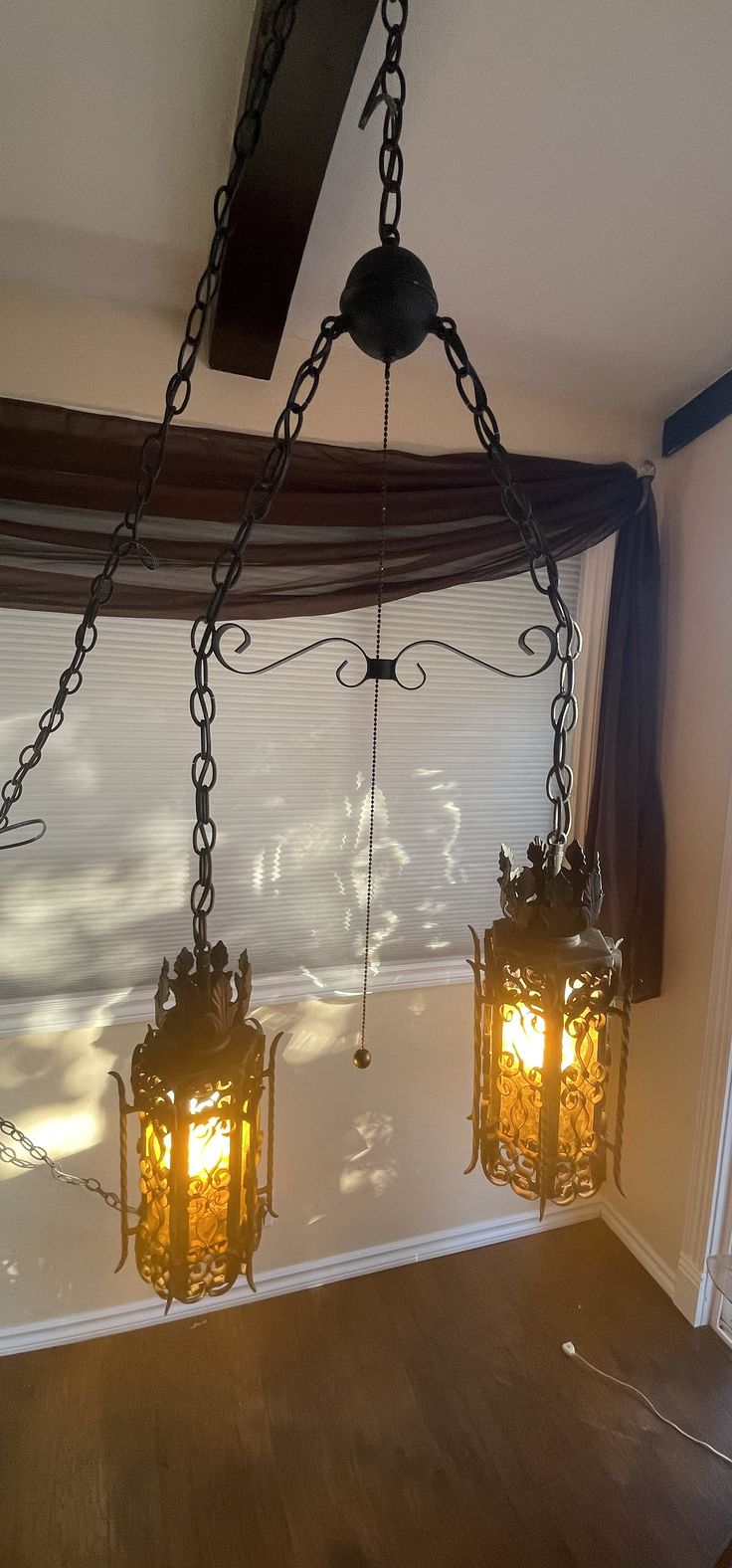 three lights hanging from the ceiling in a room with wood flooring and blinds on the windowsill