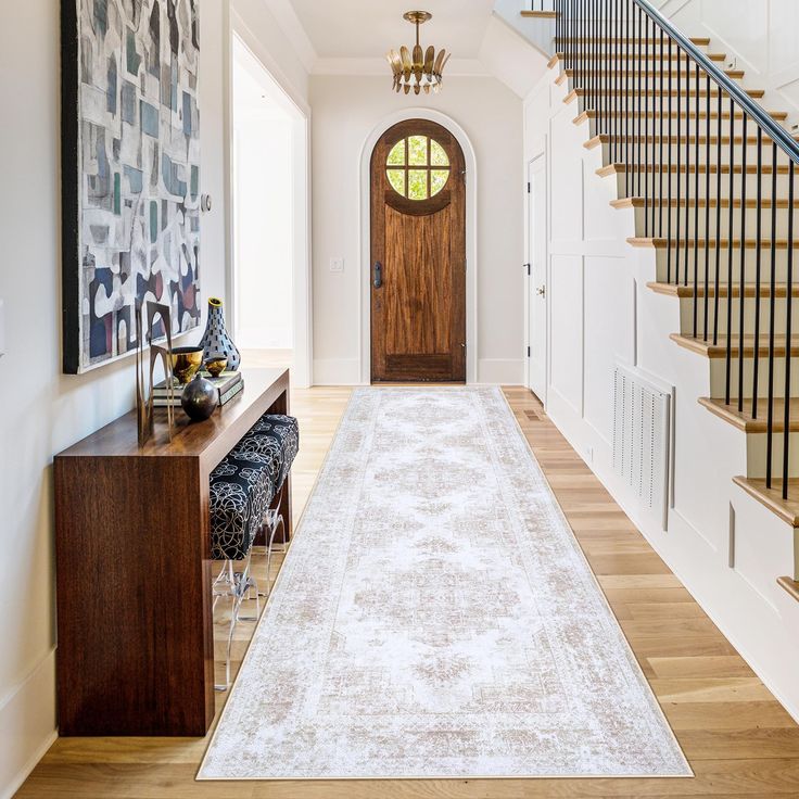 a large white rug is on the floor in front of a wooden door and stairs