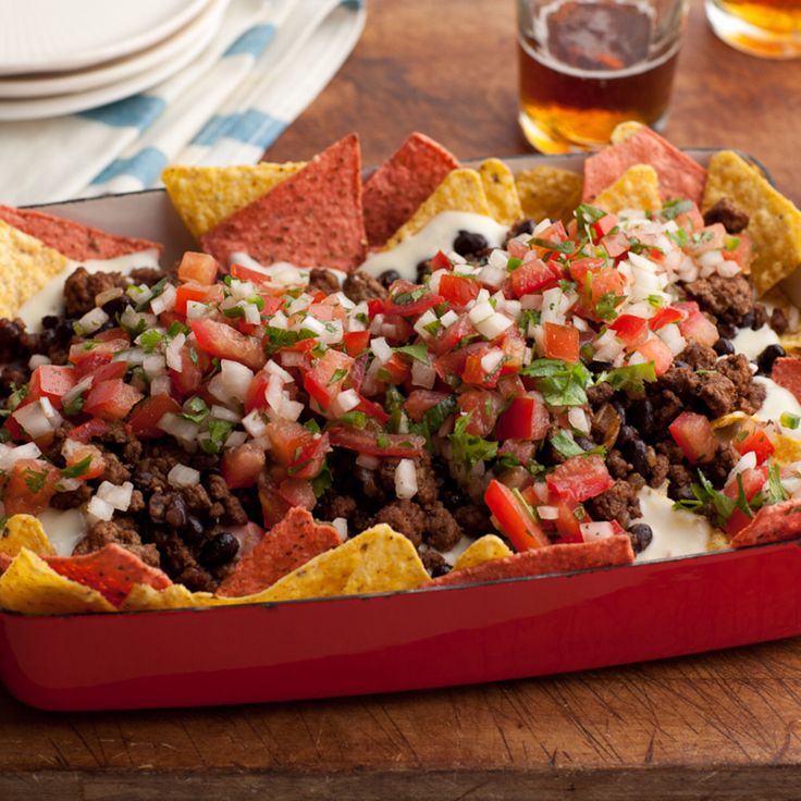 nachos in a red dish with toppings on top and the caption national nacho day