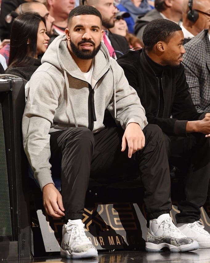 a man sitting on top of a basketball court next to another man wearing white sneakers