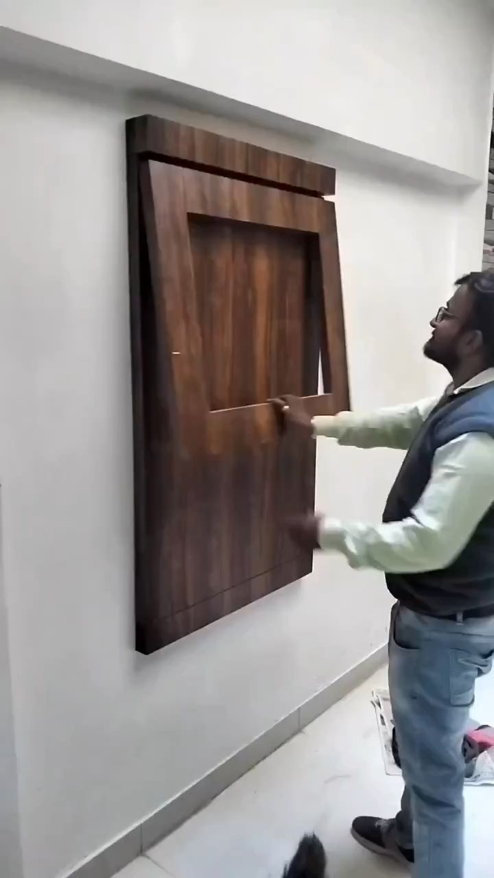 a man standing in front of a wooden door with a cat on the floor next to him