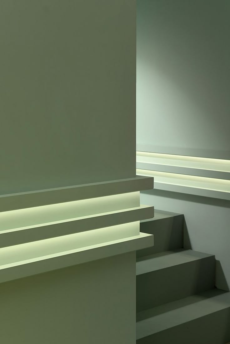 an empty room with some stairs lit up by light coming from the ceiling and on to the wall