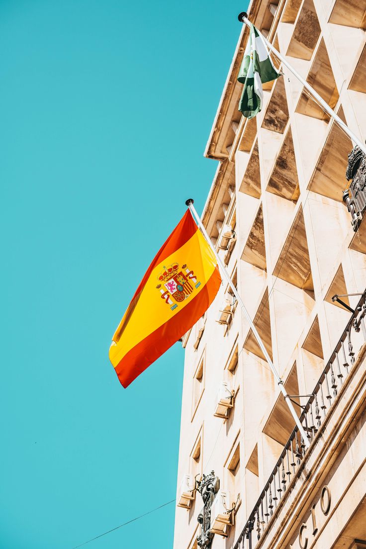 the spanish flag is flying in front of a building