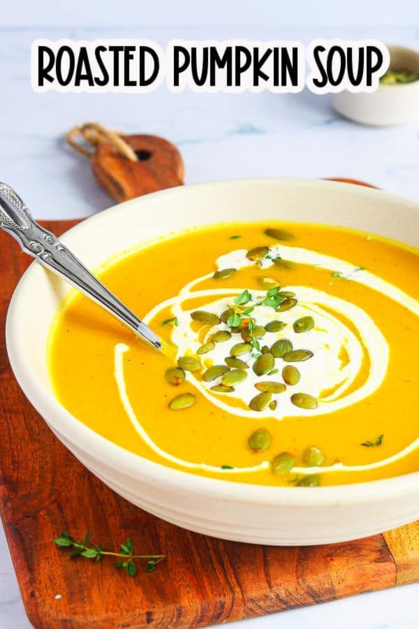 a bowl of roasted pumpkin soup on a cutting board with a spoon in it and the title overlay reads roasted pumpkin soup