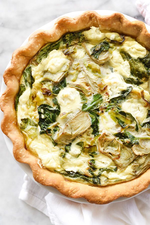 a quiche with broccoli and spinach in a pie crust on a white plate