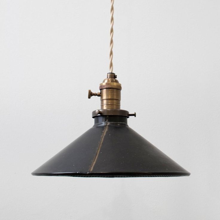 a black and gold light hanging from a ceiling with a white wall in the background