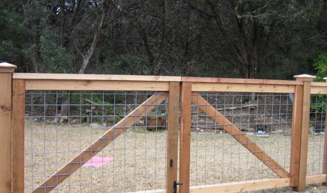 a wooden fence with wire on it and a pink object in the grass next to it