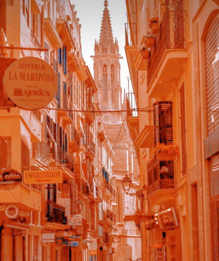 an orange city street with buildings on both sides and a clock tower in the background