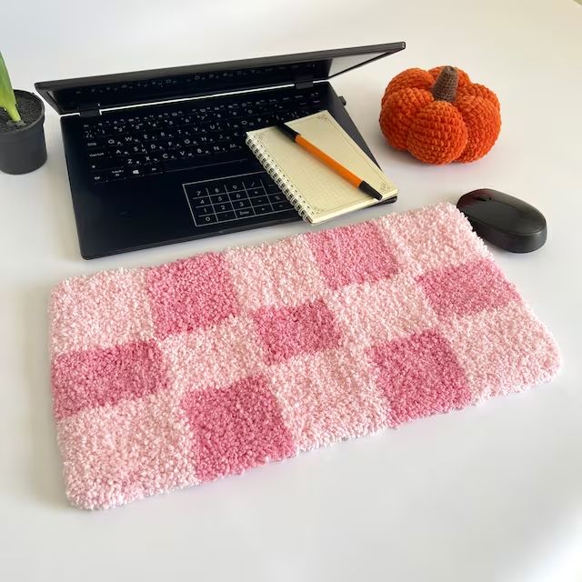 a laptop computer sitting on top of a desk next to a pink and white rug