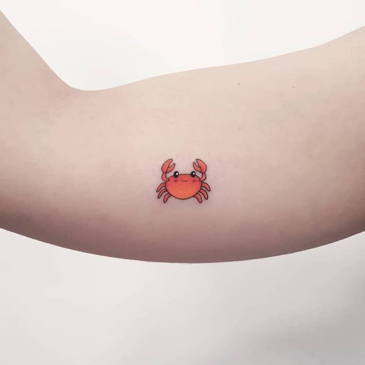 a crab tattoo on the left arm and right arm with an orange crab drawn on it