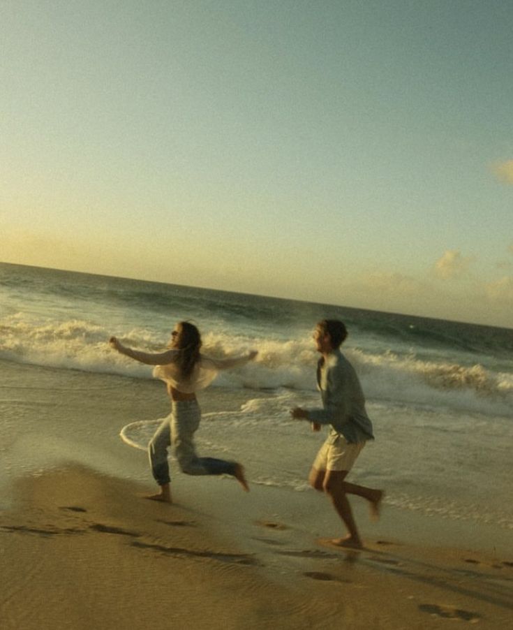 two people running on the beach near the ocean