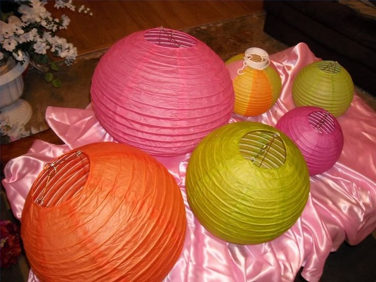 there are three balls on the table with pink and orange ribbons around them, as well as some fruit