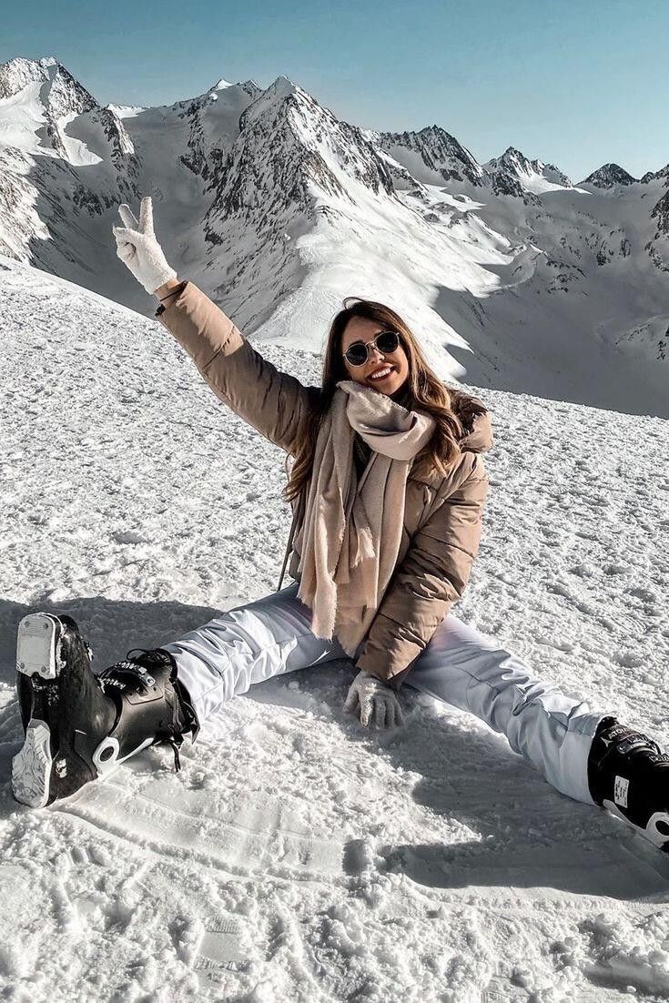 a woman sitting on top of a snow covered slope