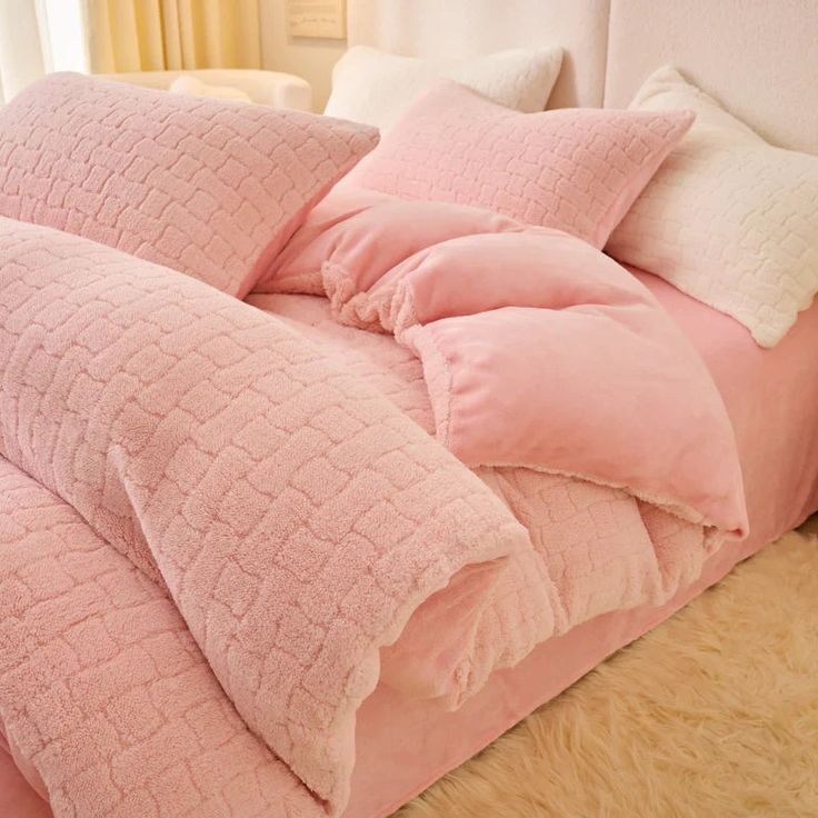 a bed with pink comforters and pillows on it