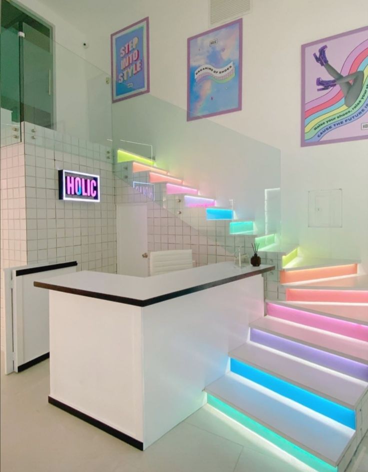 the stairs are lit up with neon lights in this white tiled room, and there is a counter that has an illuminated sign on it