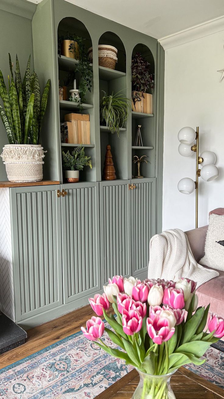 a vase filled with pink tulips sitting on top of a table next to a couch