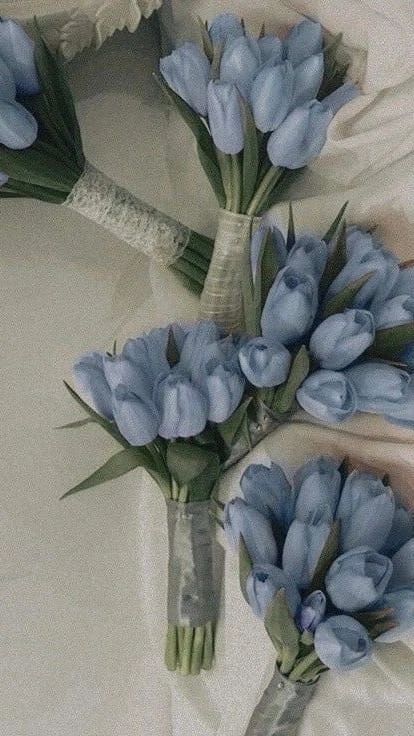 two bouquets of blue flowers are laying on a bed