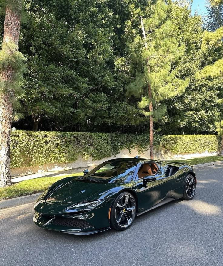 a green sports car parked on the side of the road in front of some trees